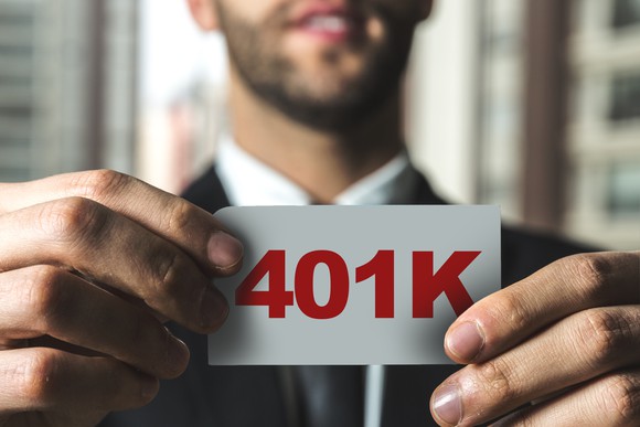 Man holding small white piece of paper with 401K in red printed on it