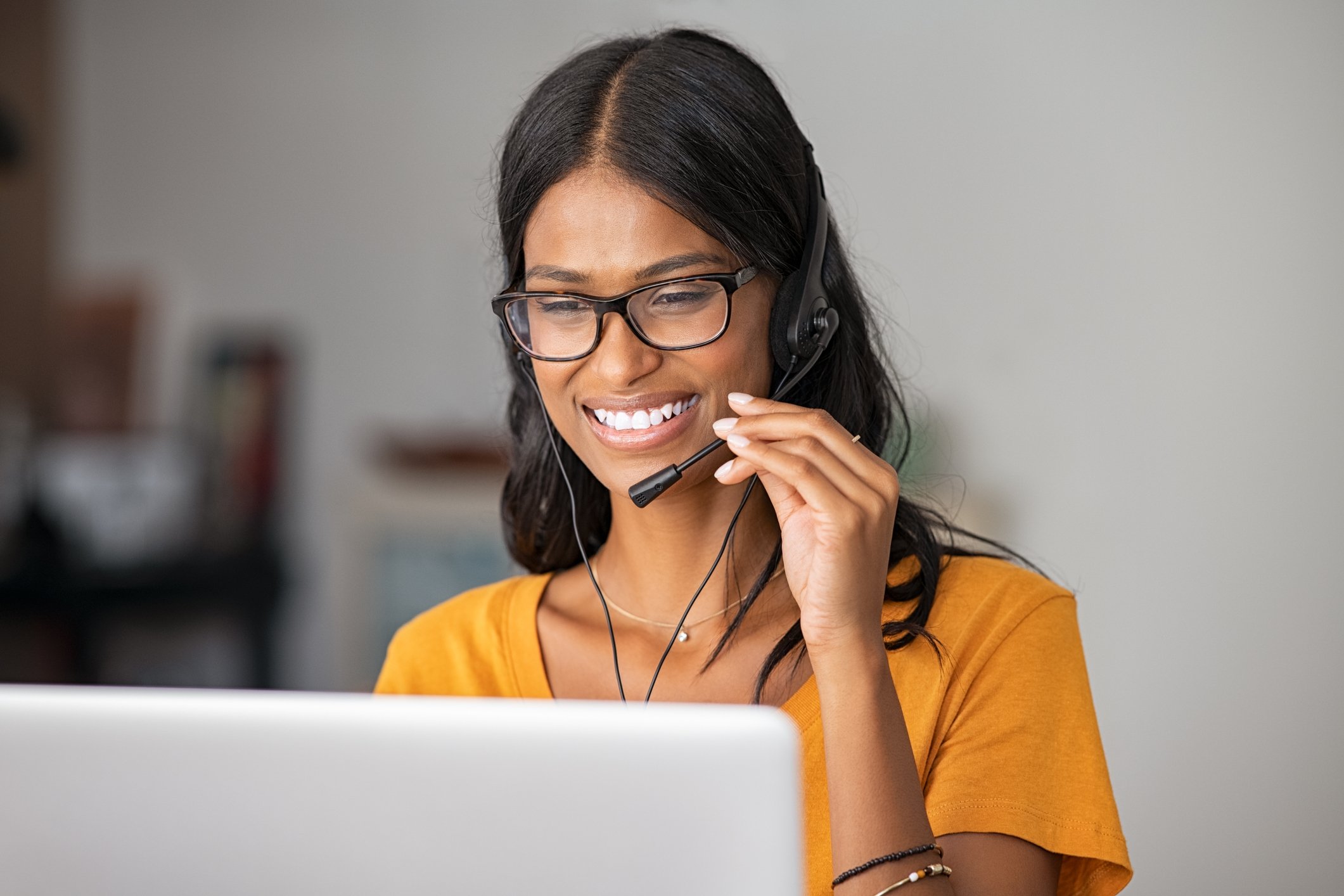 Young woman wearing a headset while serving a customer remotely.