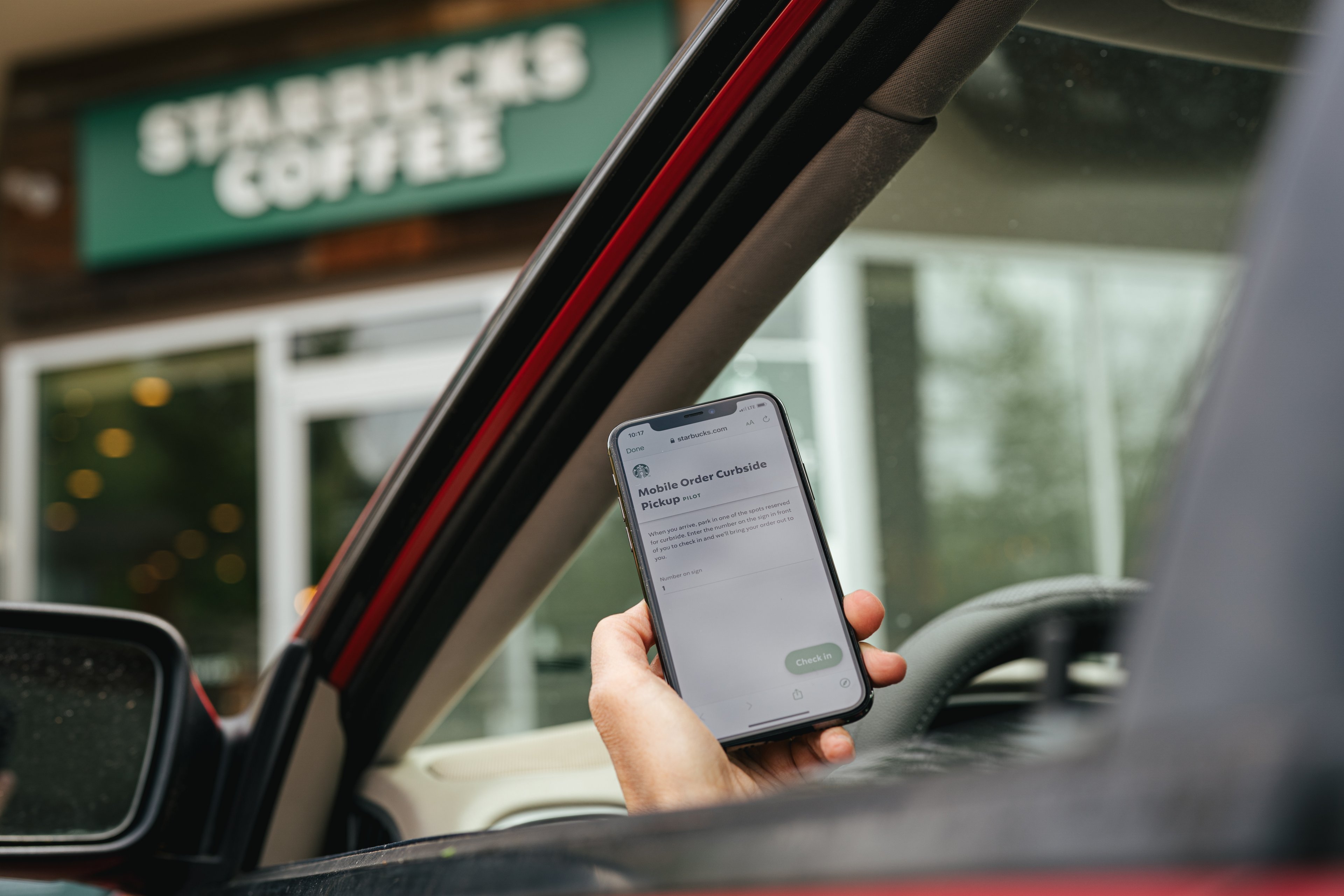 Person in car outside Starbucks store, ordering on phone