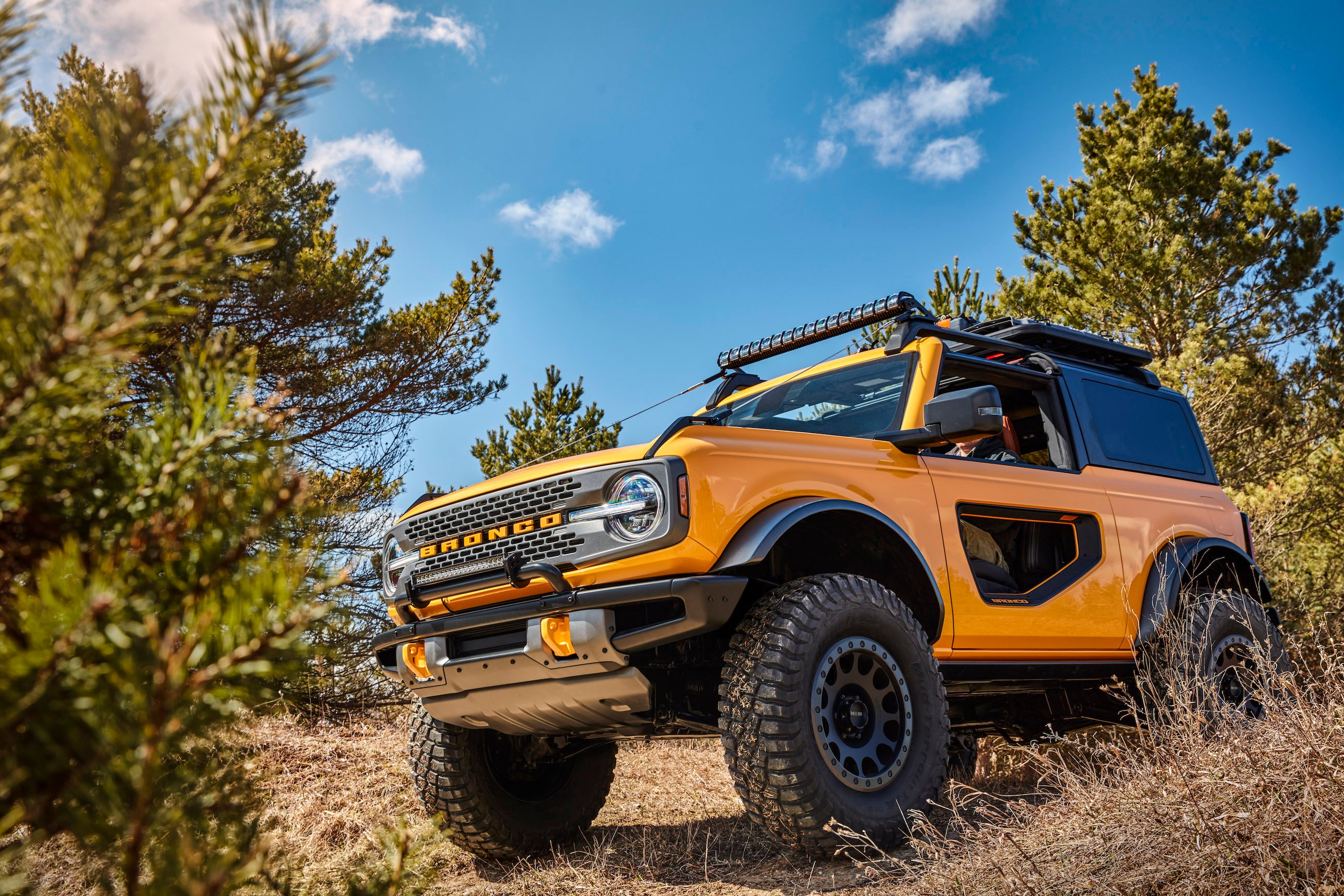 A yellow 2021 Ford Bronco, an off-road SUV, on a hillside. 