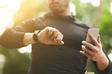 A man using a fitness tracker and smartphone