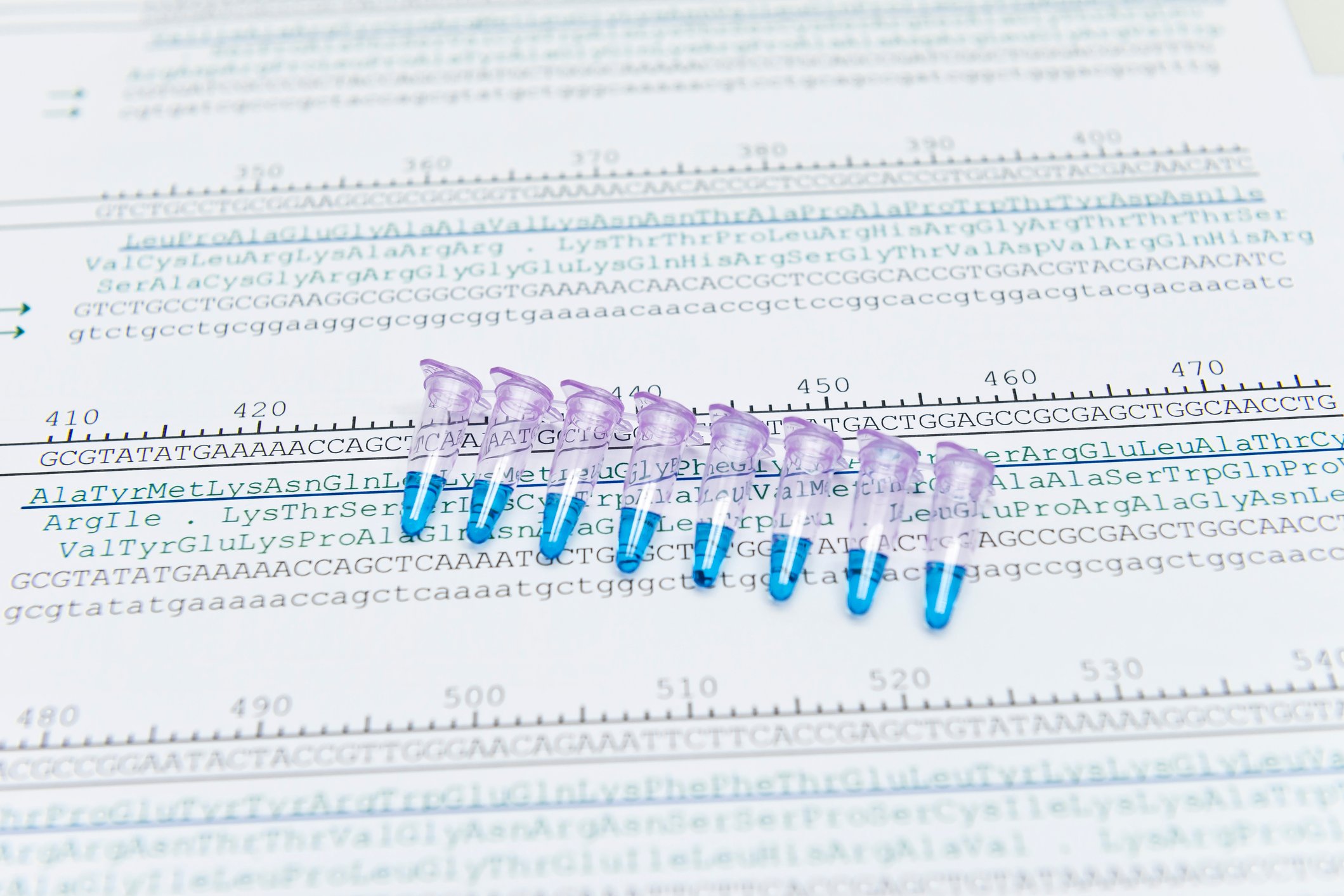 A series of test tubes laid on top of a page with genetic sequences.
