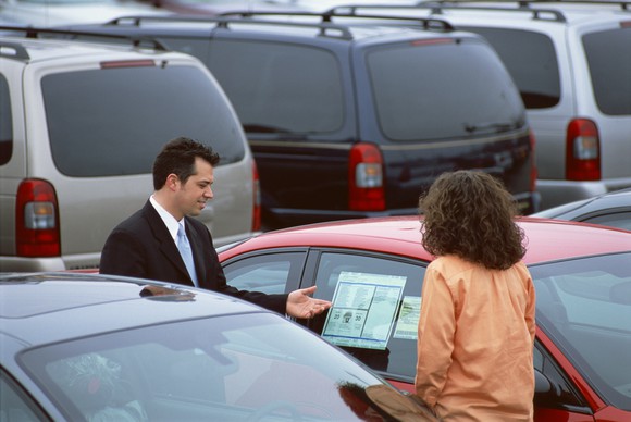 Two people looking at car in sale lot