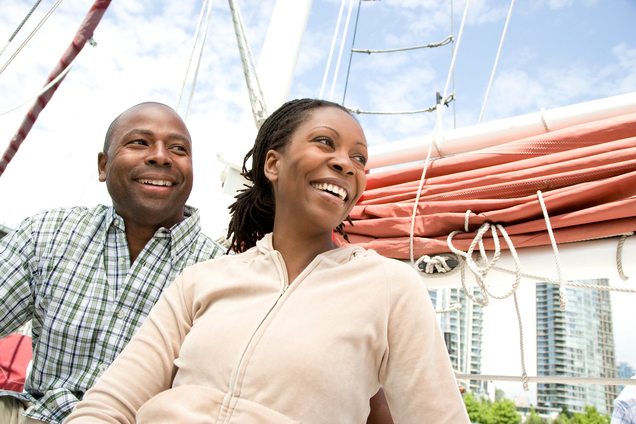 A couple sits on a sailboat at port. 