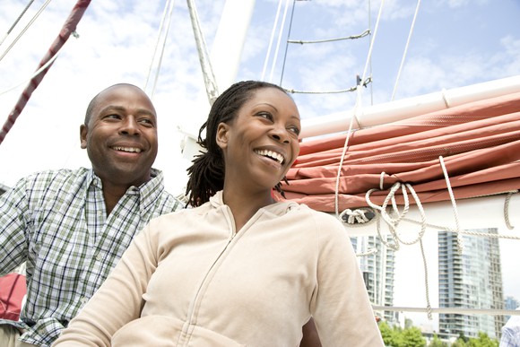 A couple sits on a sailboat at port. 