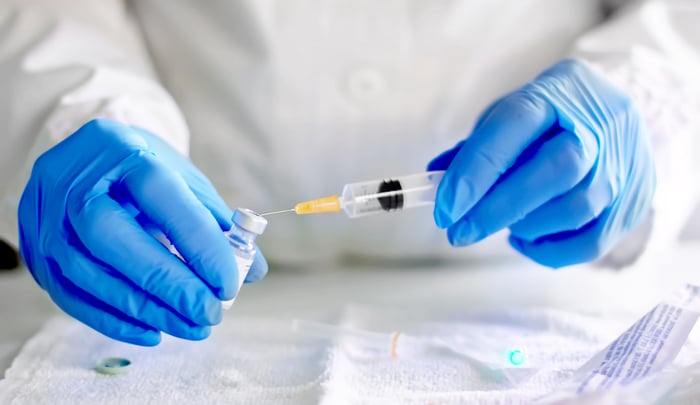 A researcher draws a dose of vaccine from a vial.