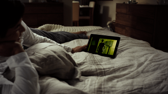 A person laying in bed watching video on a tablet.