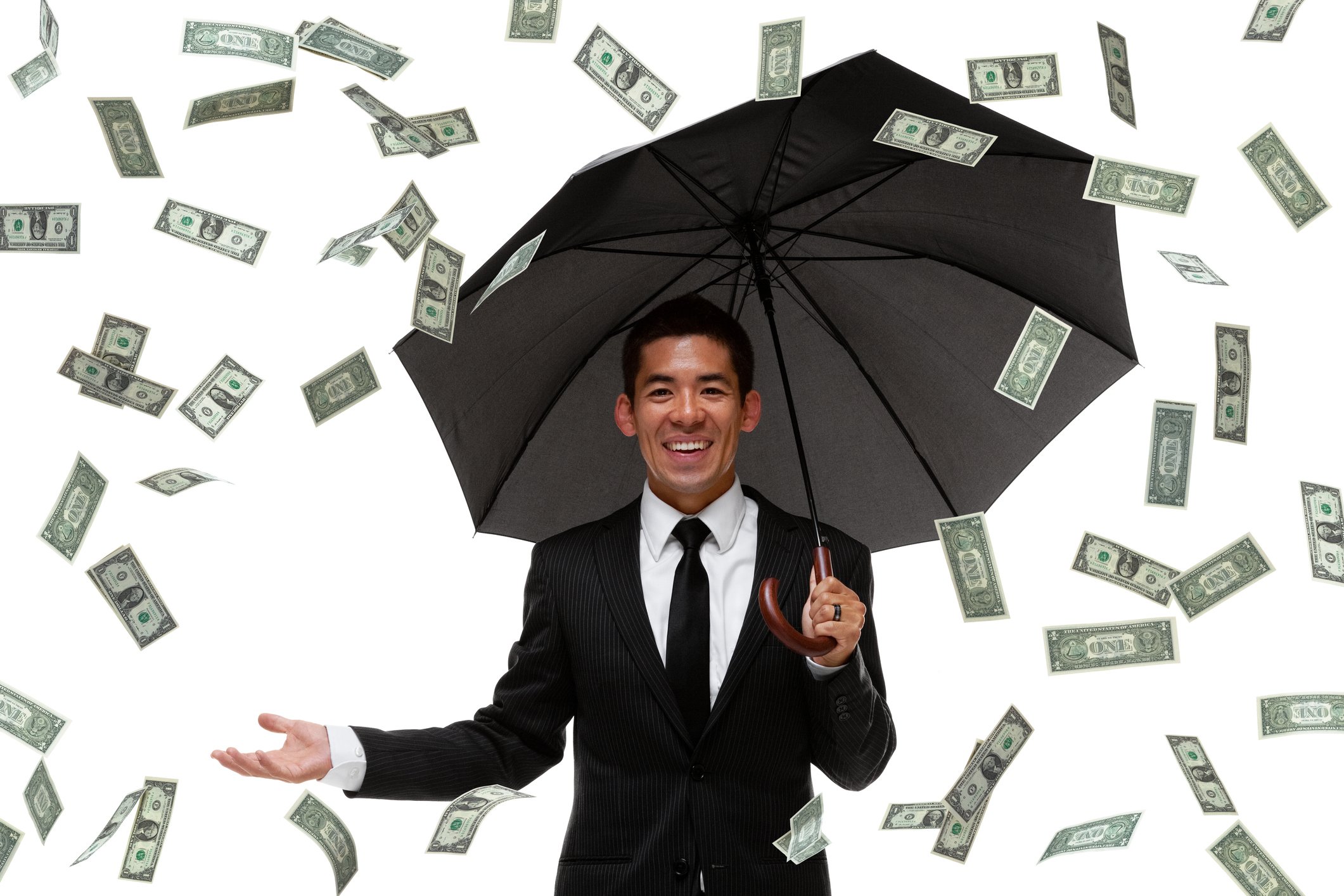 A businessman with an umbrella under a rain of dollar bills