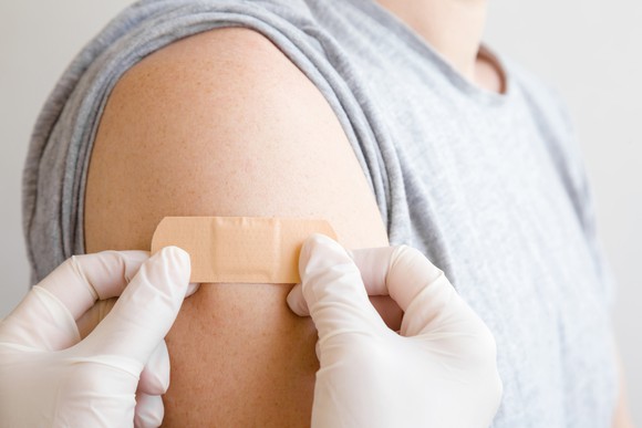 A researcher places a bandage on a person's arm after a vaccination.