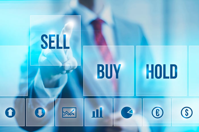 Businessman pointing to "sell" icon" next to "buy" and "hold" icons