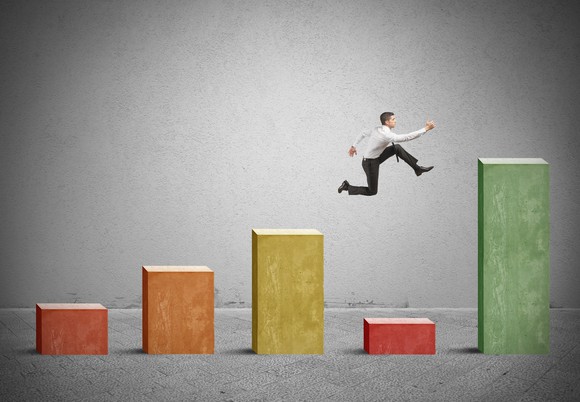 A man leaps to avoid one low bar among a series of increasing bars.