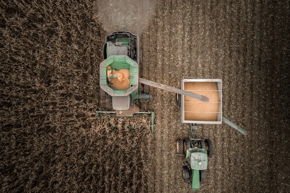 An overhead view of a tractor and combine moving through a corn field.