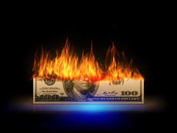 Bottom half of a $100 bill lit on fire.
