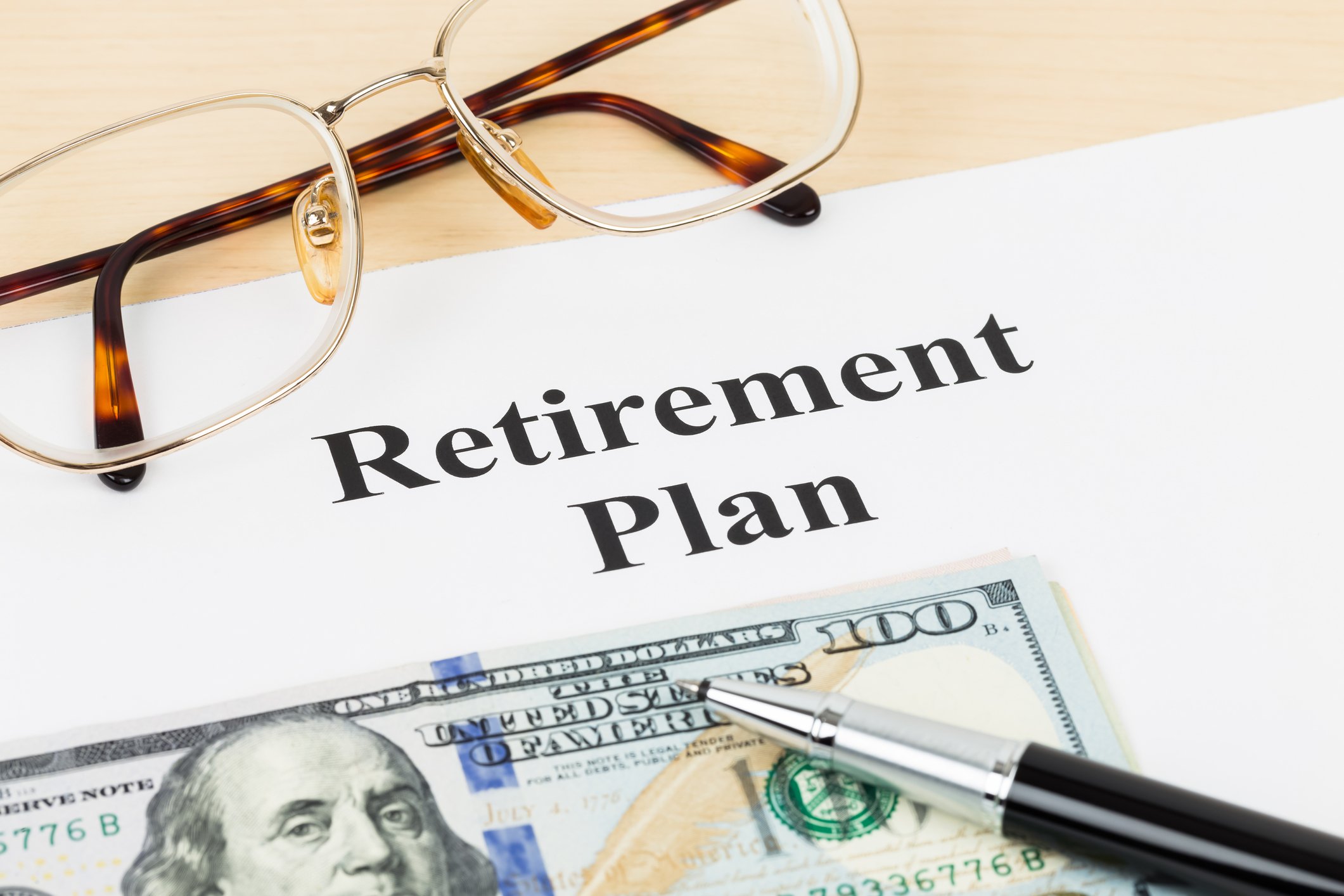 A pair of reading glasses on a paper with the title "Retirement Plan."