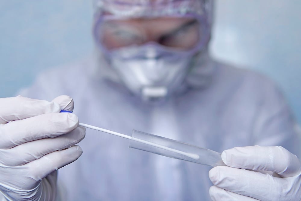 A healthcare worker holds a swab for a coronavirus test