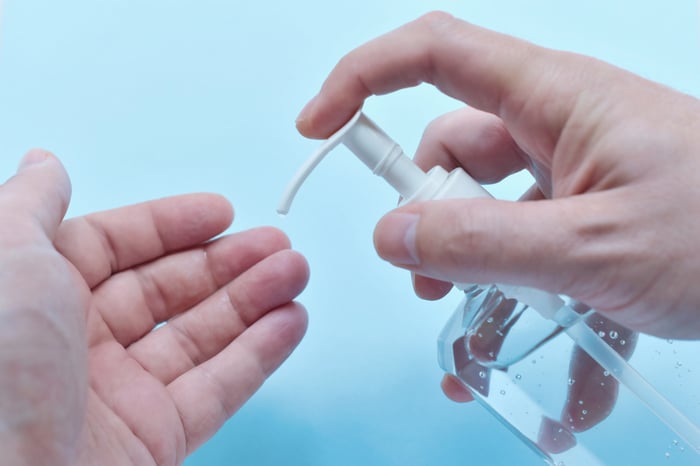 Someone dispensing hand sanitizer from a bottle into their palm.