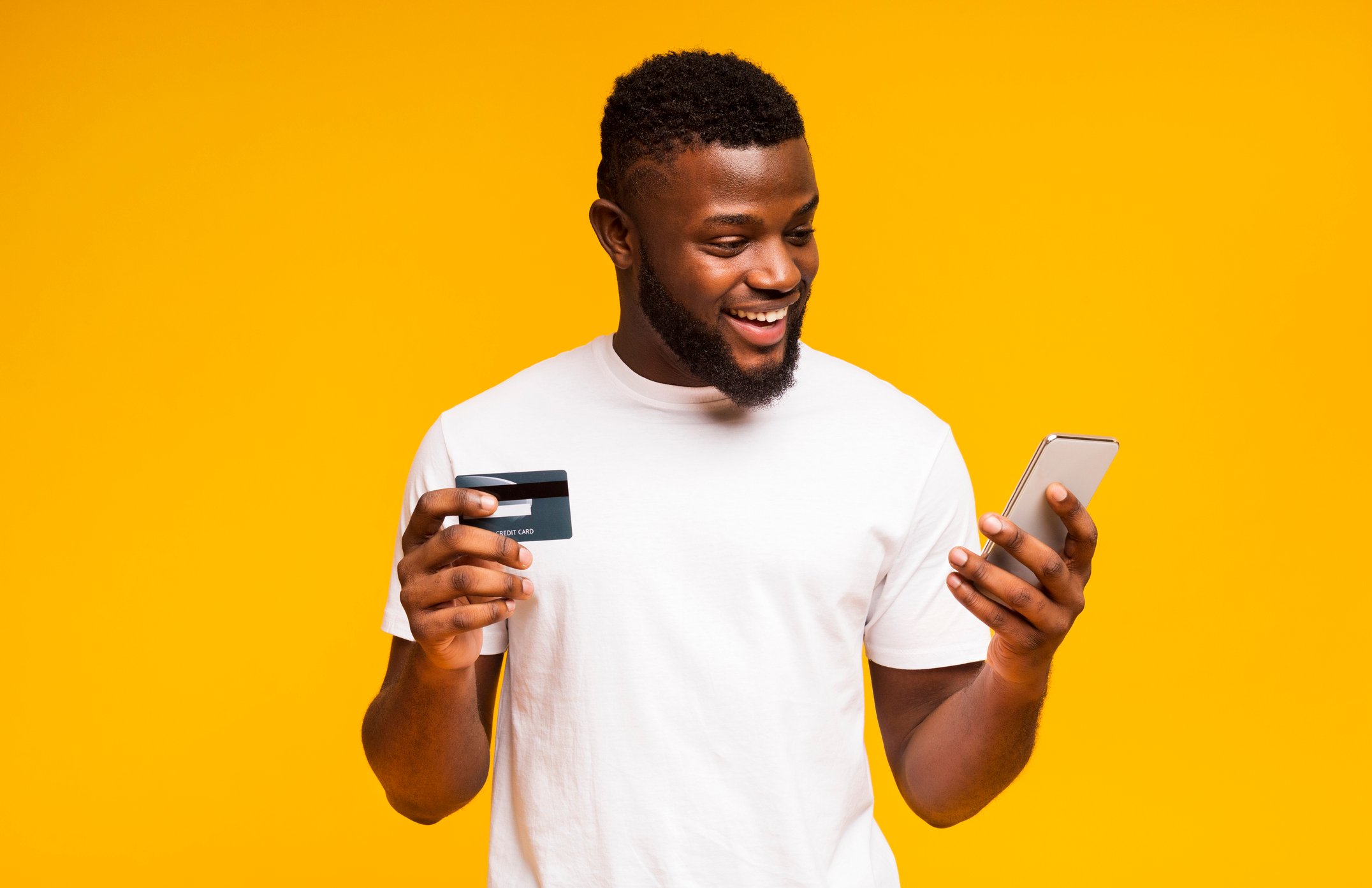 Happy man buying merchandise with a credit card through his smartphone.