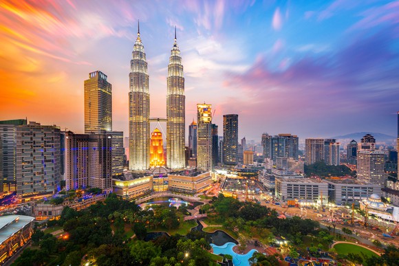 Kuala Lumpur cityscape with skyscrapers and other buildings overlooking landscaped area. 
