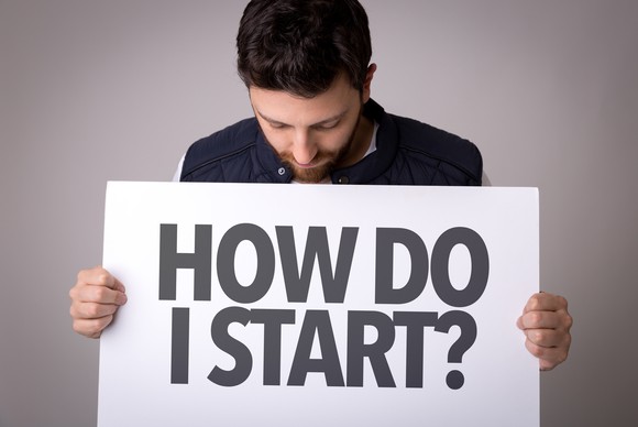 Man holding sign that reads, "how do I start?"