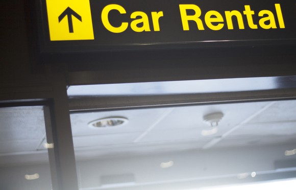 An airport sign pointing travelers to car rental kiosks. 