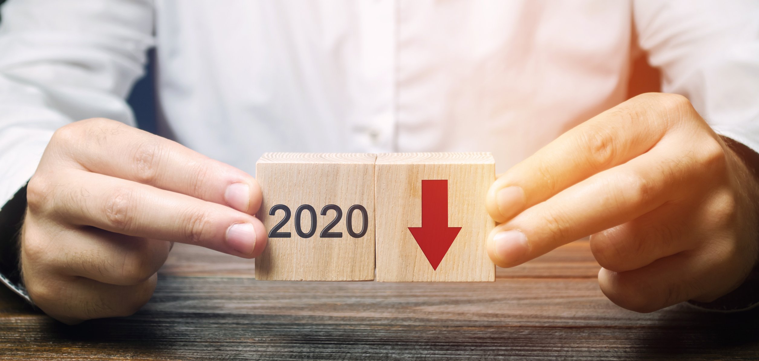 An investor holds blocks marked 2020 with an arrow pointing downward.