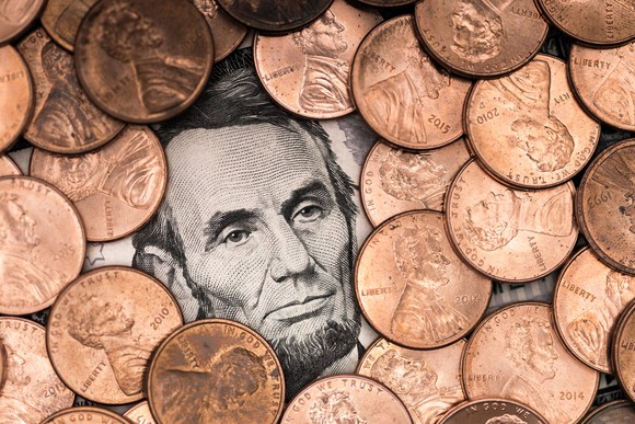 A pile of pennies surrounding Abraham Lincoln's face on a five-dollar bill.