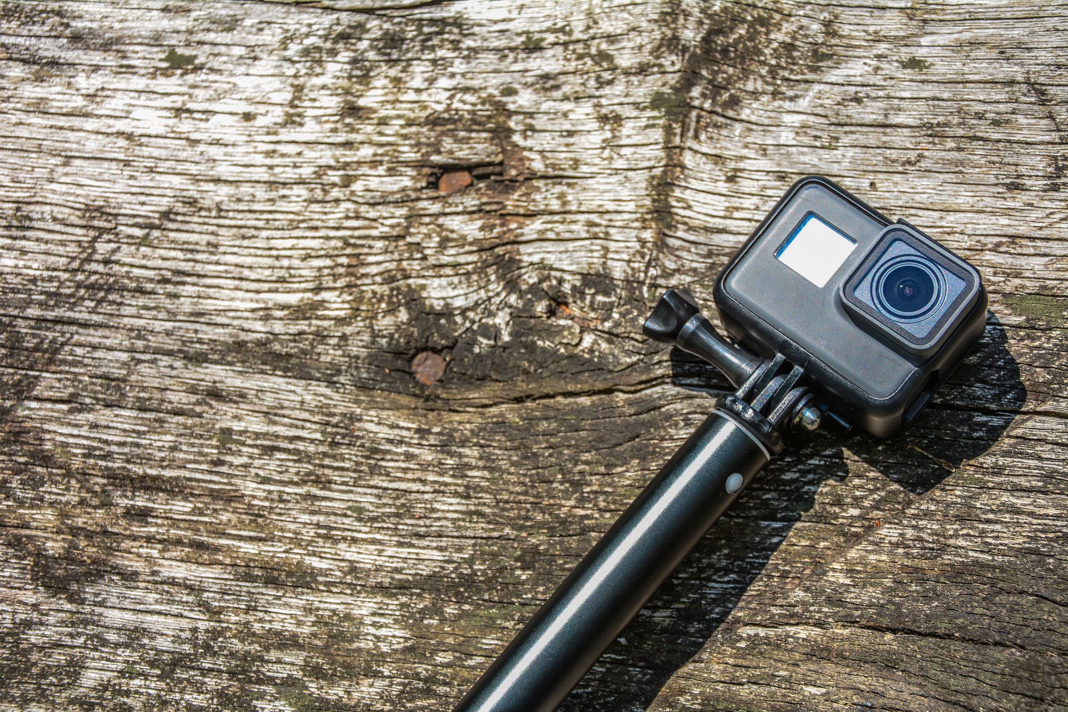 An action camera lying on a wooden plank.