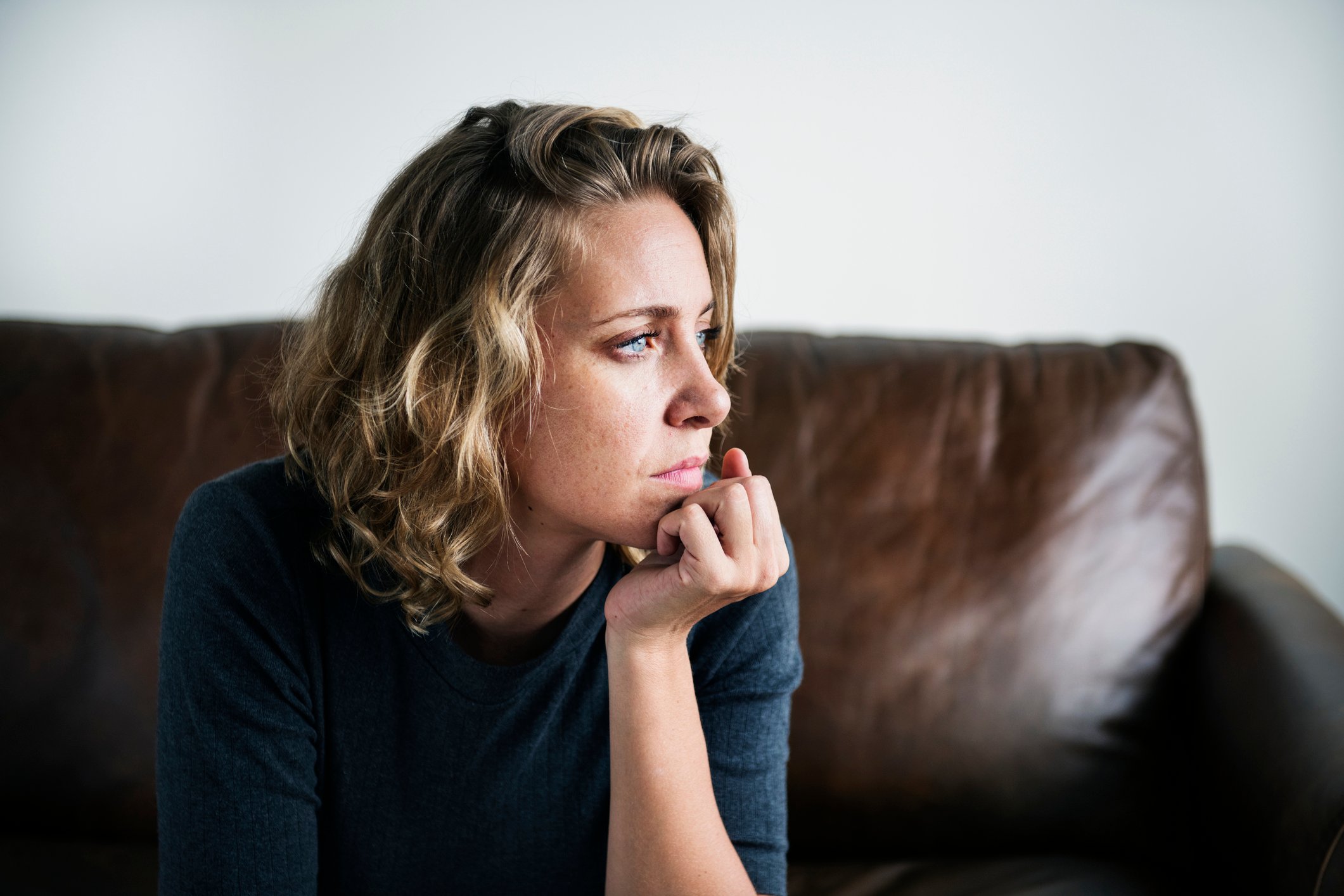 Woman thinking with her chin resting on her hand at home.