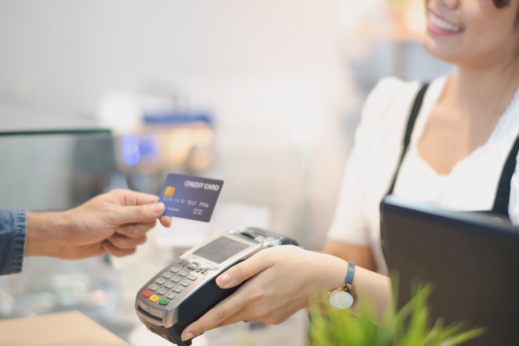 A person paying a vendor with a credit card as she holds up a card-swipe device. 