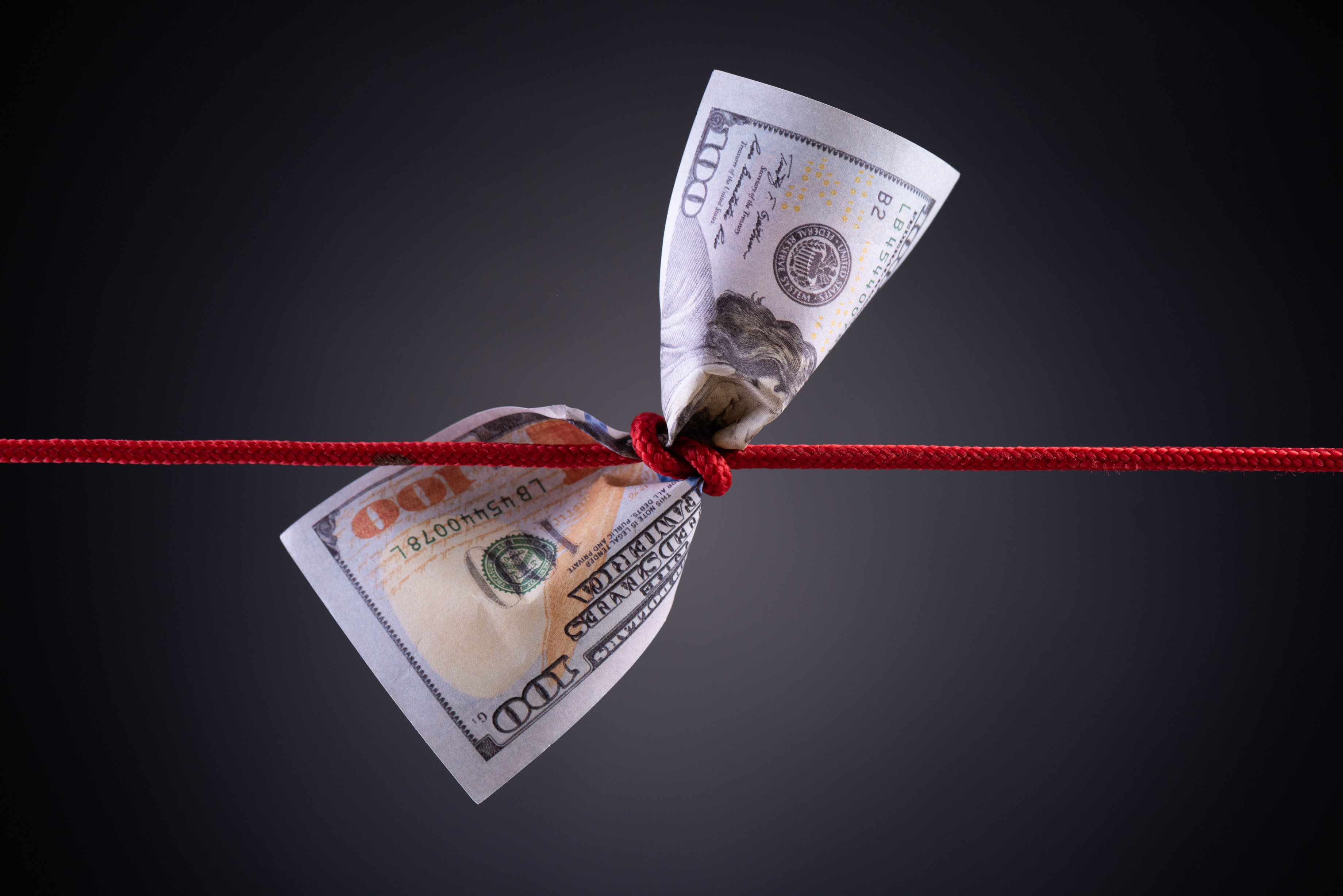 A red string knotted around a hundred-dollar bill.