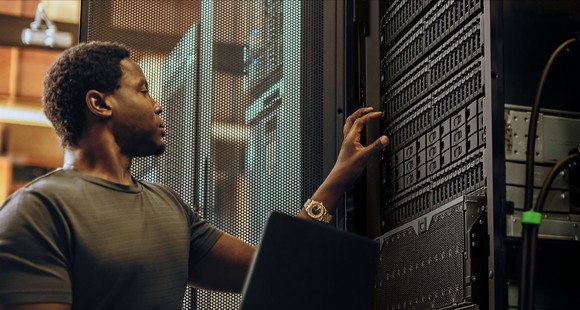 A man working on hard drives inside a data center.