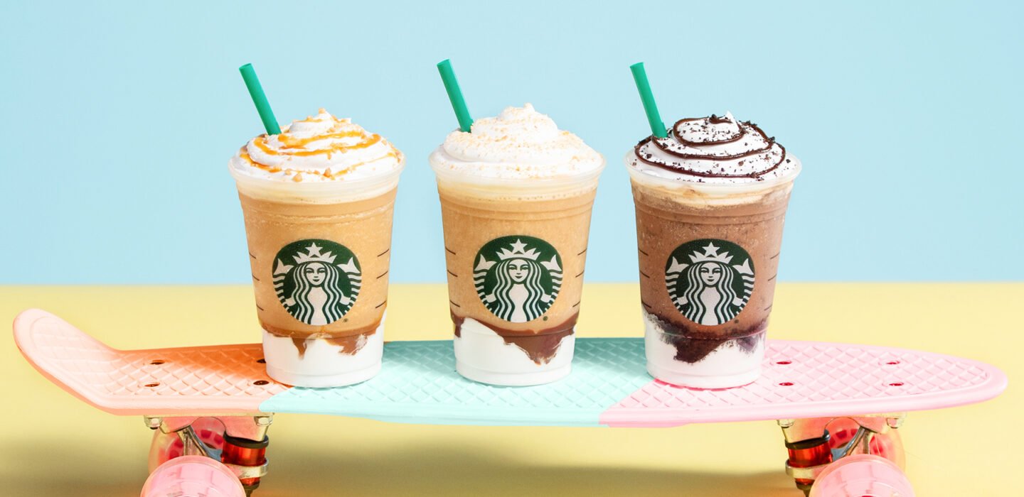 Three Starbucks Frappuccinos sitting on a skateboard