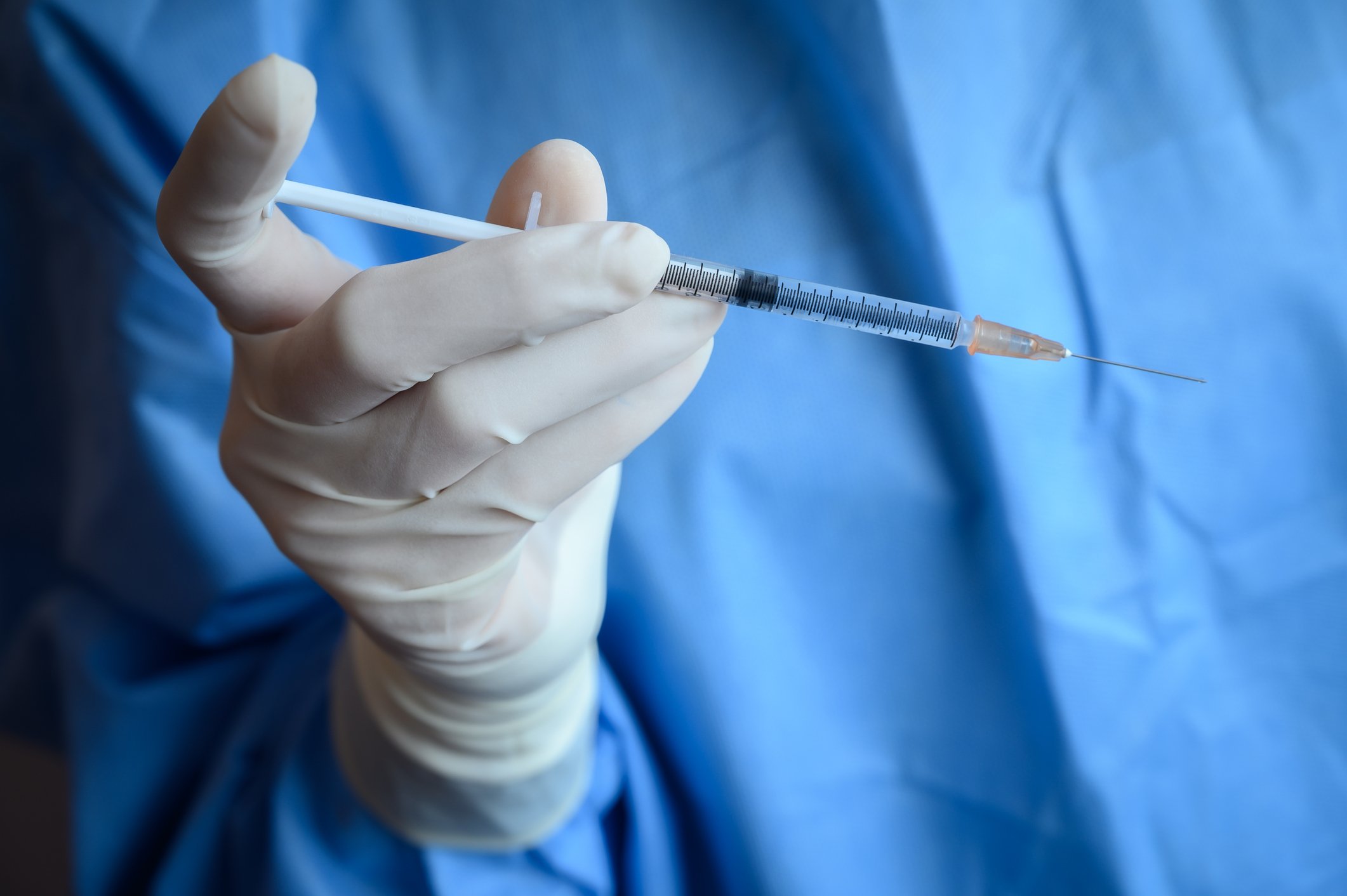 A researcher holds a syringe filled with vaccine.
