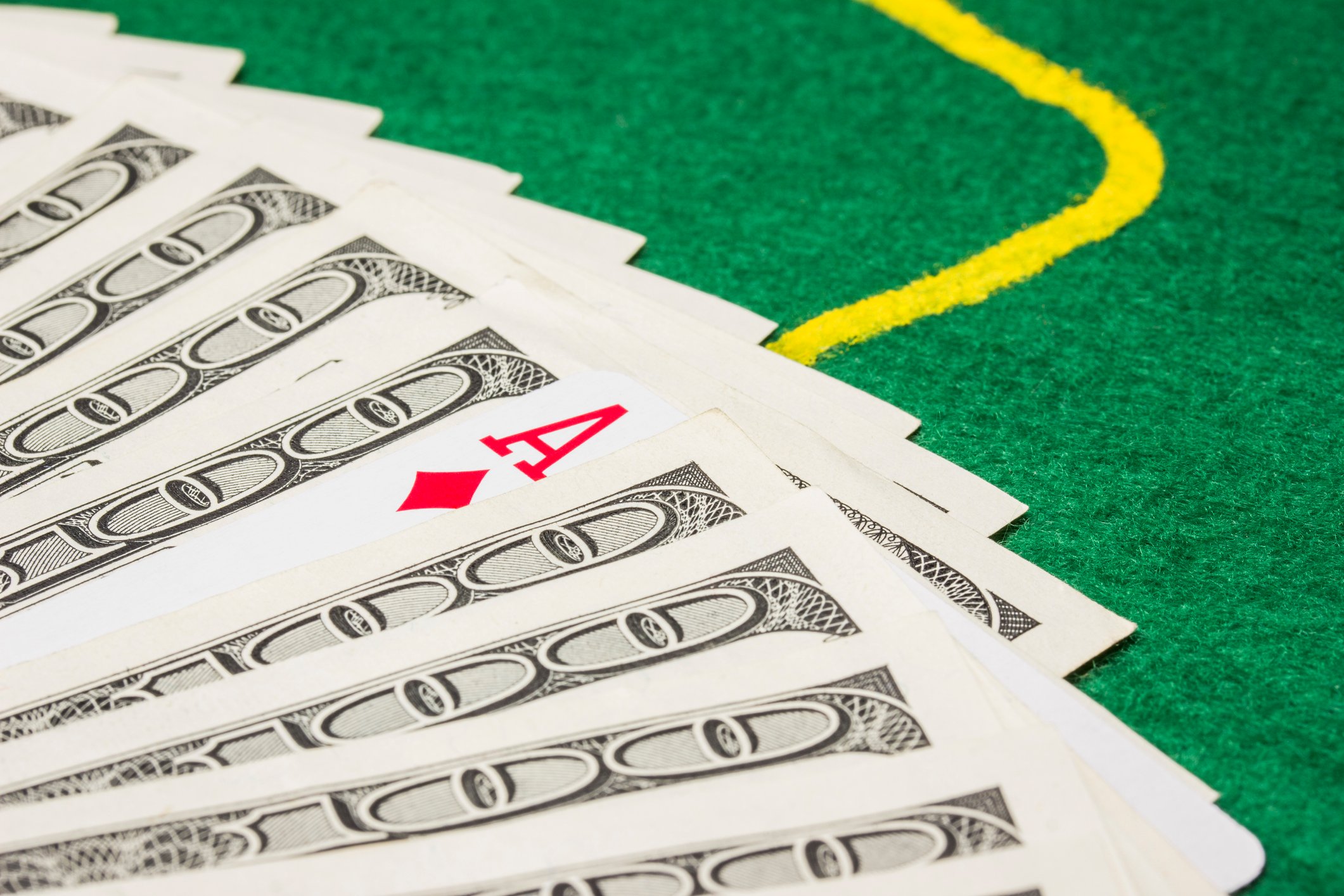 An ace and hundred dollar bills on a gaming table.