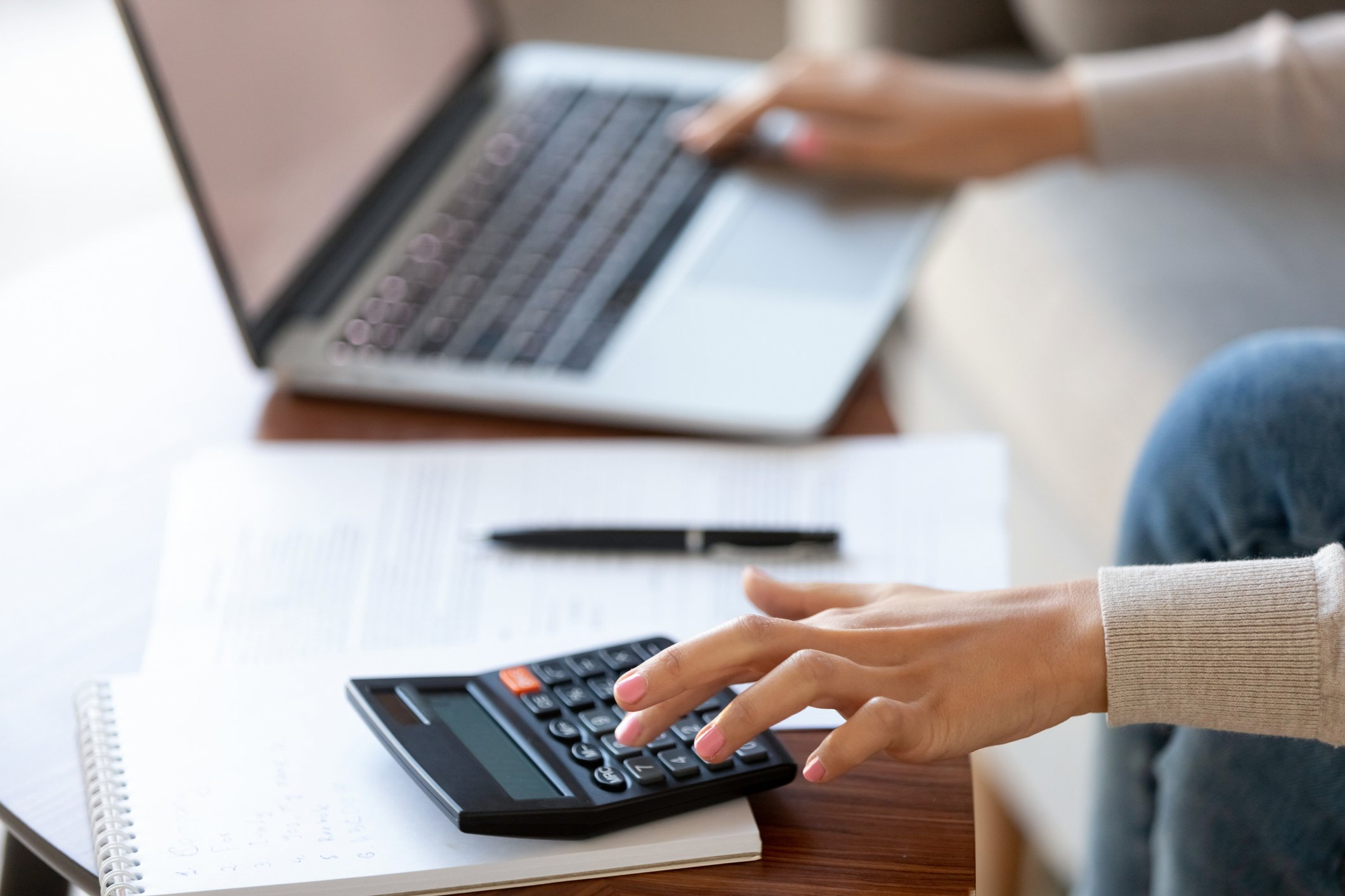 A taxpayer calculates her taxes on a calculator and laptop.
