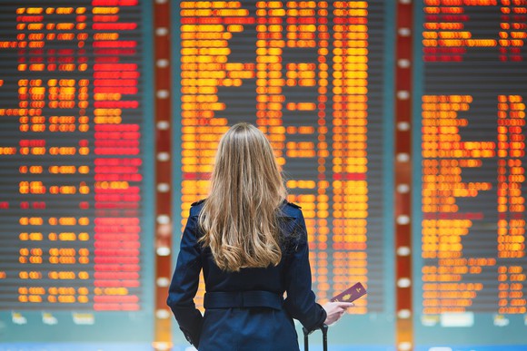A woman looks at the board in an airport for flight information.