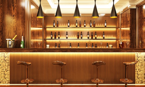 An empty bar with stools in front and bottles behind it.