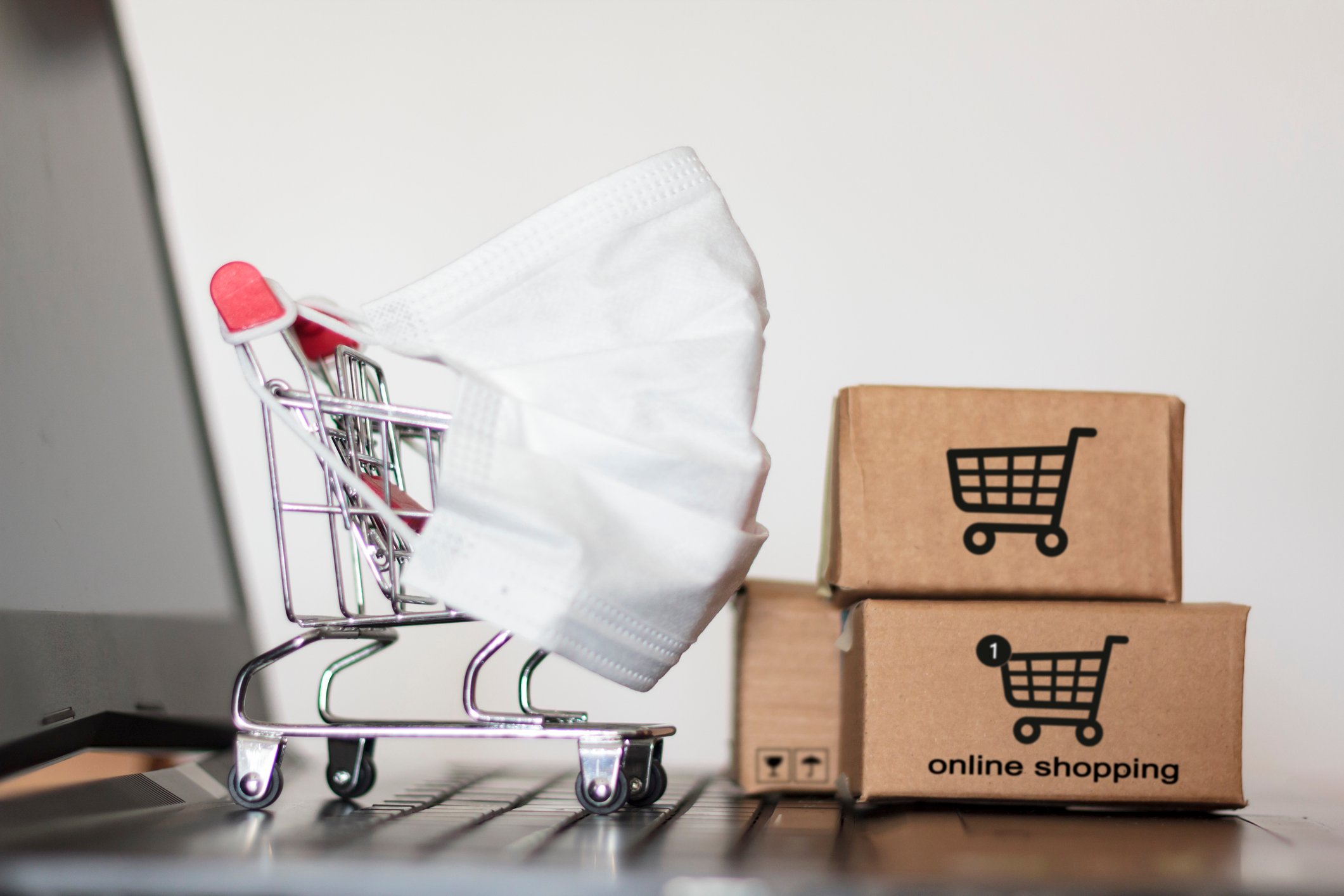 A shopping cart outfitted with a mask next to three small boxes.