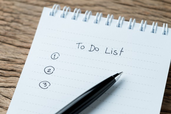 Pen resting on a paper pad with a blank to-do list written on it. 