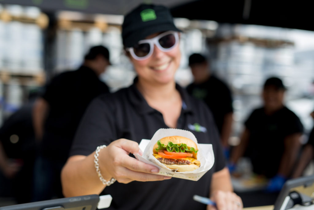 A Shake Shack employee holds up a burger.