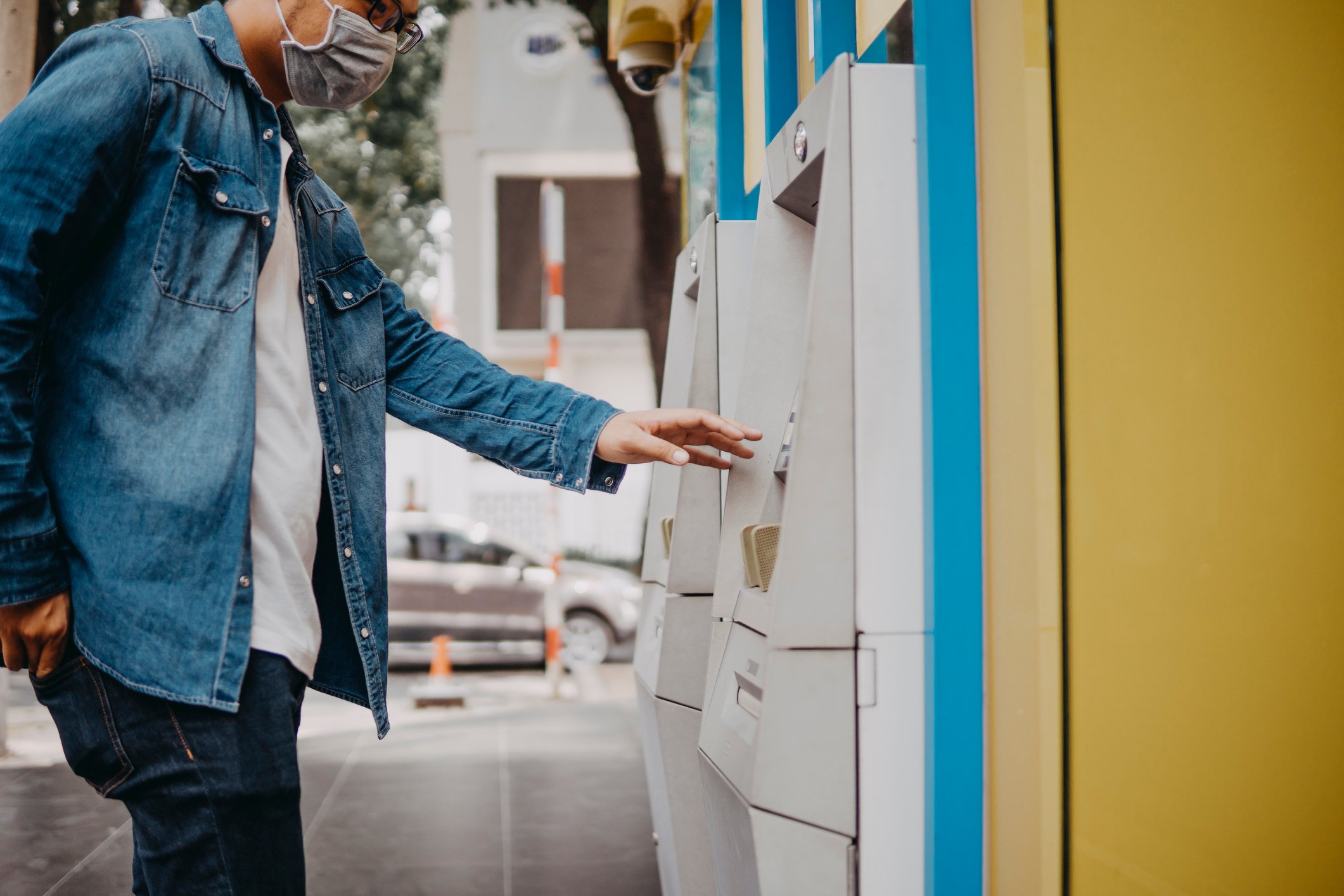 A consumer wears a mask and works an ATM machine. 