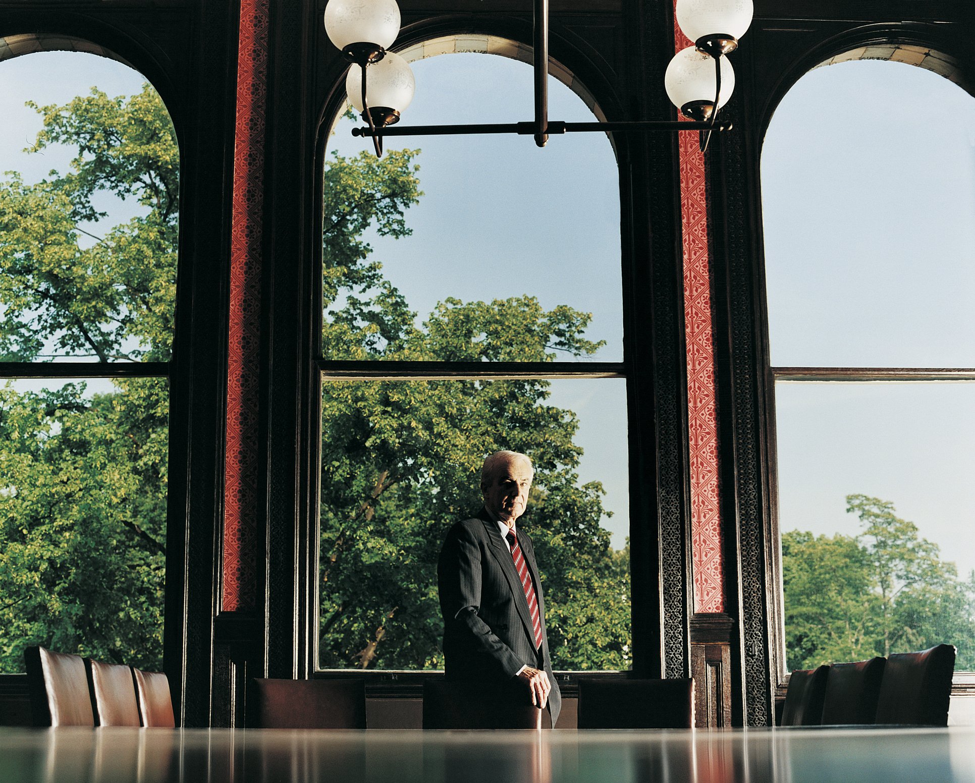 Older CEO standing commandingly at the head of a conference room table