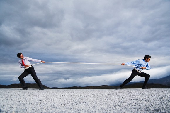 Two businessmen engaged in a game of tug-of-war