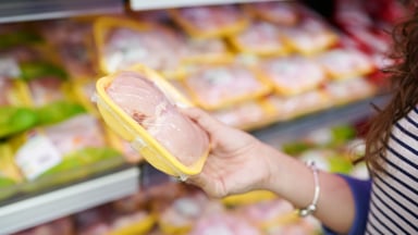 Woman selecting raw chicken at a supermarket.