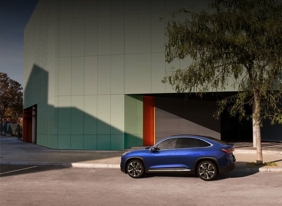 A blue NIO EC6 parked near a large building