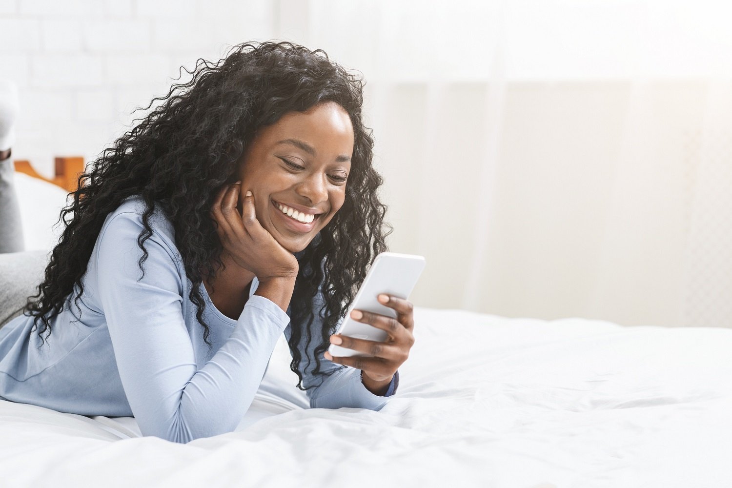 A woman smiles at her smartphone.