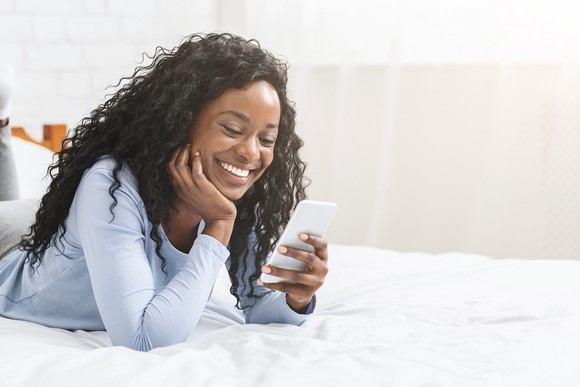 A woman smiles at her smartphone.