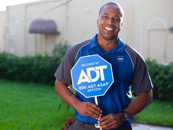 An ADT technician holding a company sign.