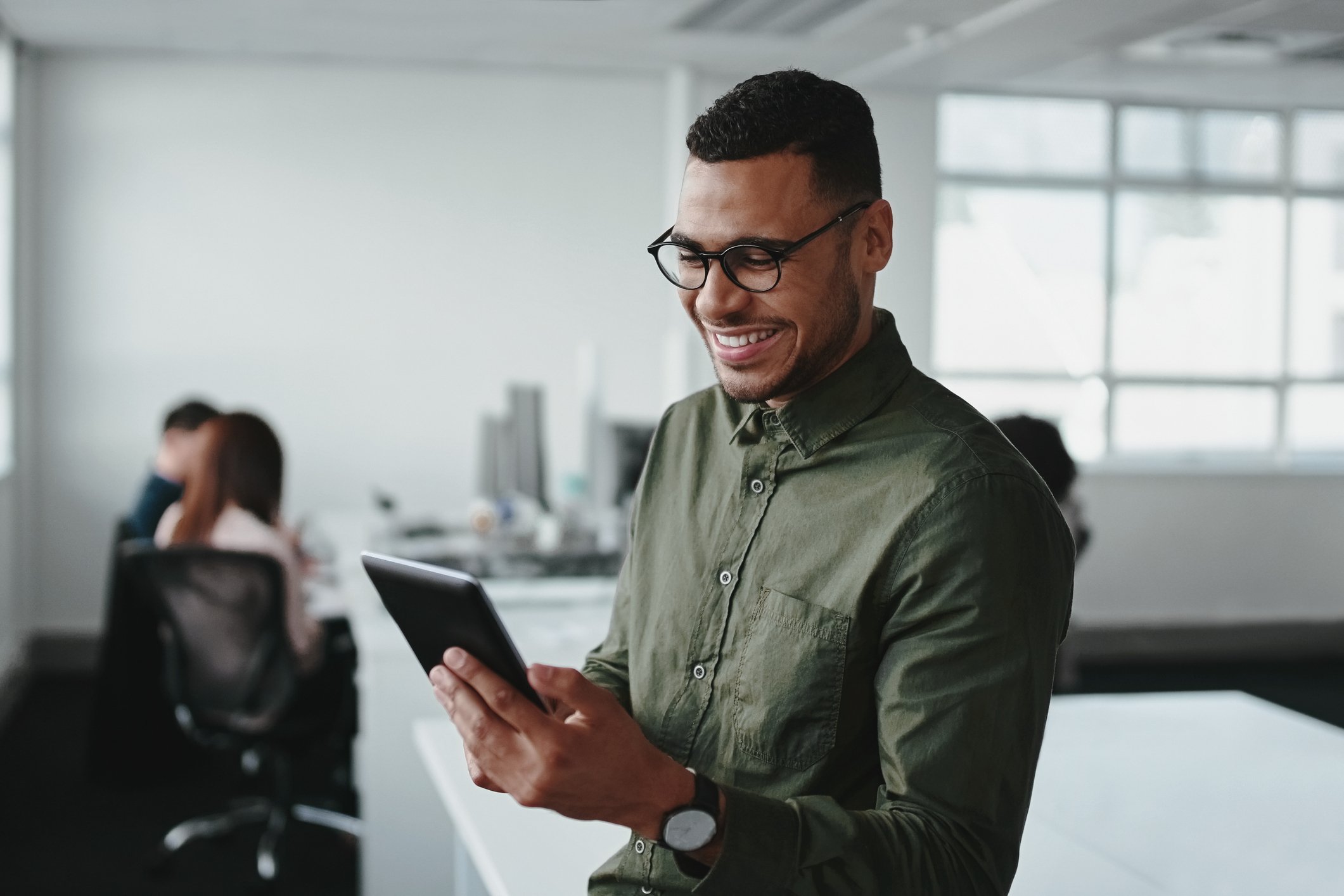 Man smiling as he stares at his smartphone at his workplace.