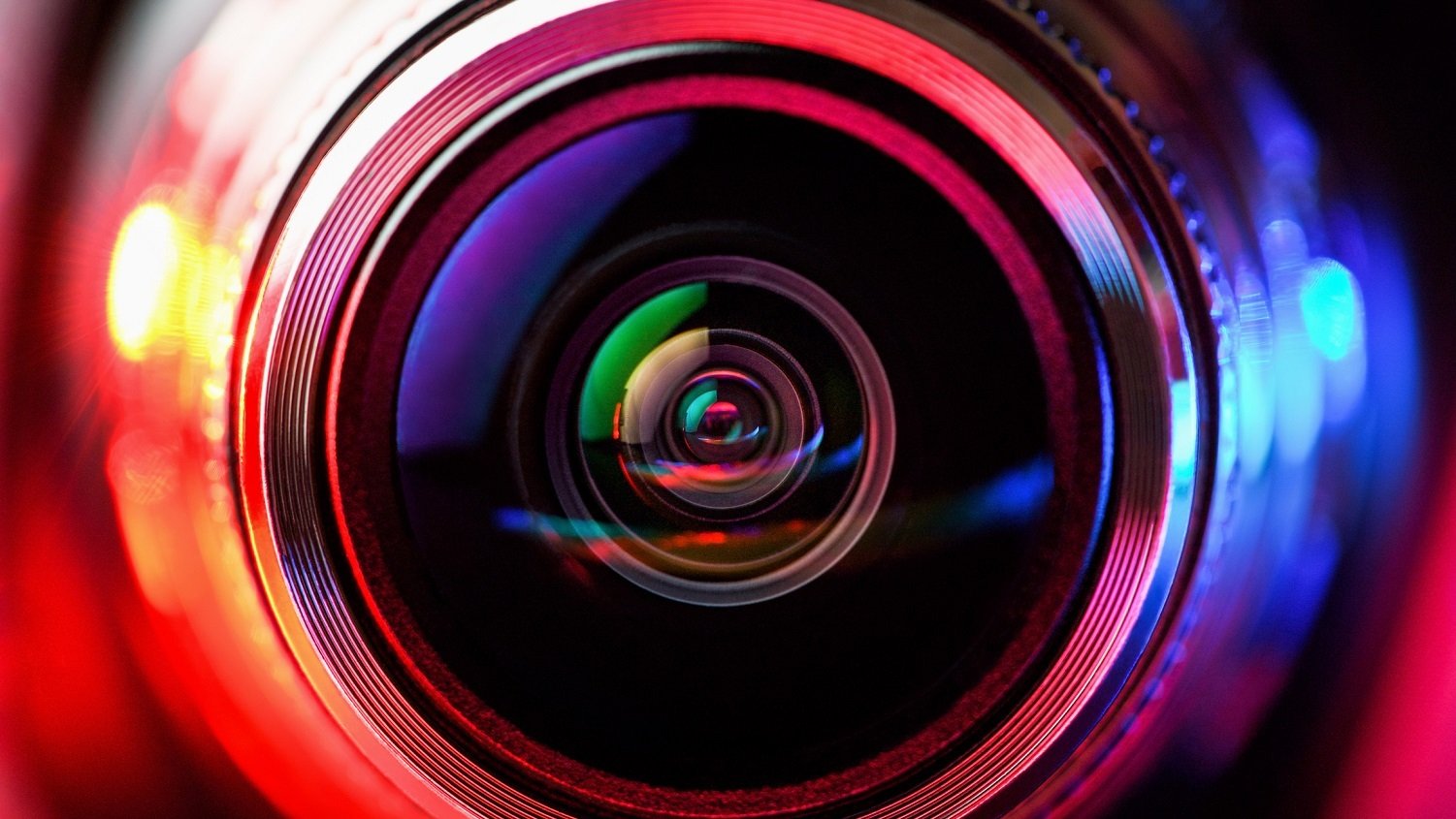 Close-up of camera lens with red light on left and blue light on right.
